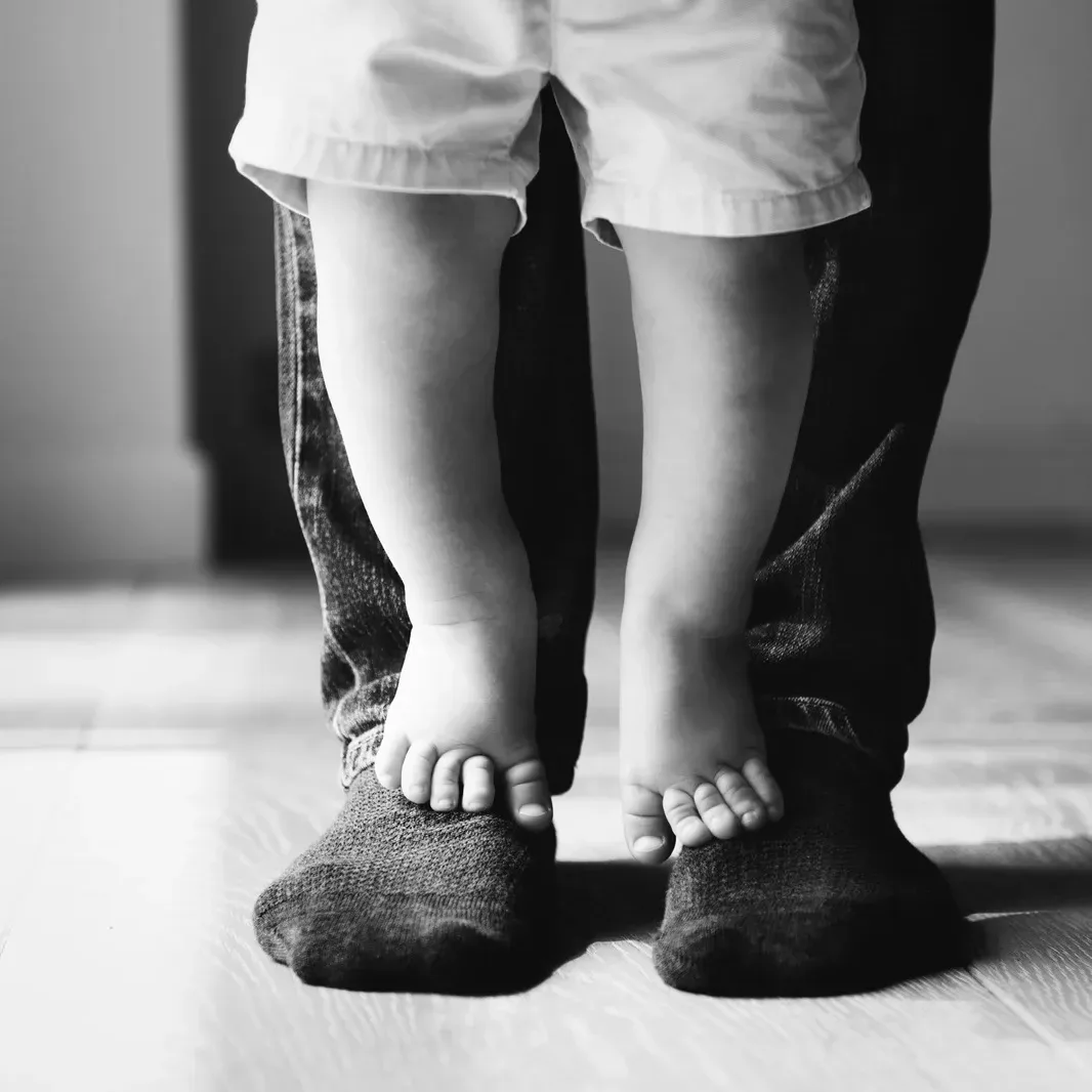 Kinderfüße auf den Füßen eines Erwachsenen